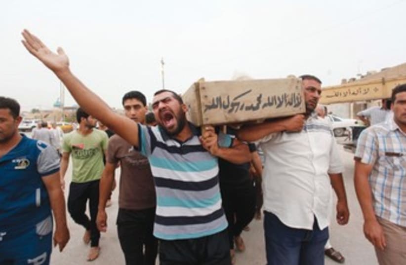 RELATIVES CARRY the coffin of an Iraqi police 370 (photo credit: Haider Ala/Reuters)