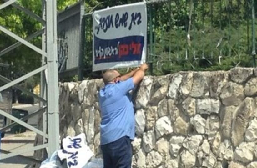Bet Shemesh worker removing campaign poster 370 (photo credit: Courtesy Eli Cohen campaign Facebook page.)