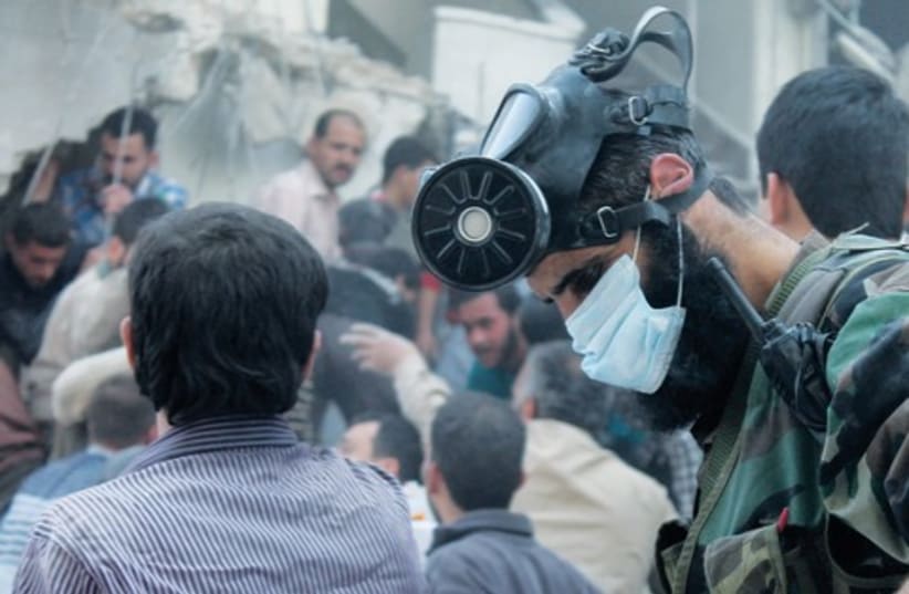 A man wearing a chemical mask searches for survivors (photo credit: Haleem Al-Halabi/Reuters)