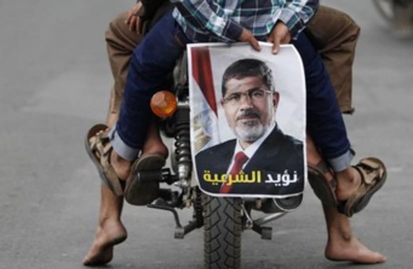 A pro-democracy supporter holds a picture of Morsi 370 (photo credit: Reuters)