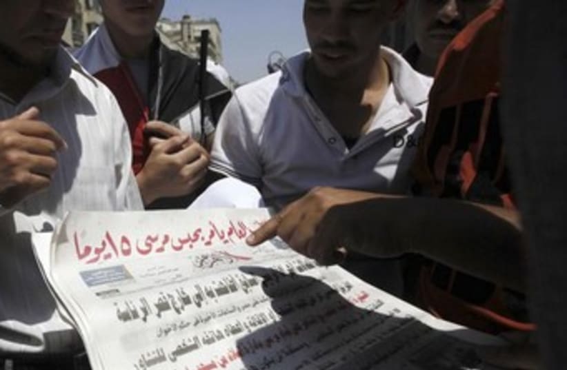 Brotherhood Morsi supporters reading Al Ahram 370 (photo credit: REUTERS/Amr Abdallah Dalsh)