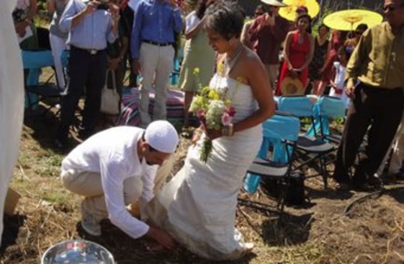 The groom washes the feet of his bride during the wedding (photo credit: Micha’el BedarShah/JTA)
