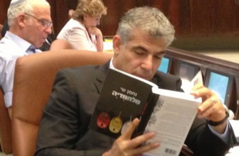 Finance Minister Yair Lapid reading 370 (photo credit: Noa Amir )