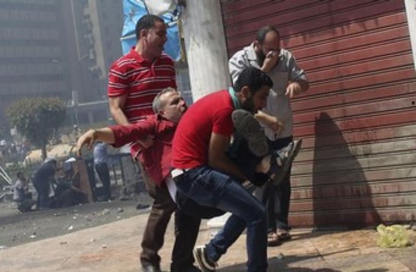 Protesters carry injured man in Cairo 370 (photo credit: REUTERS)