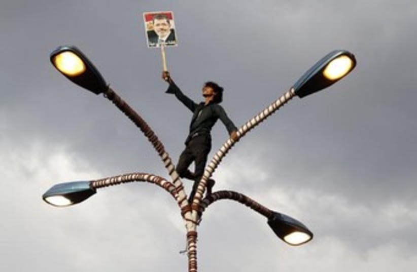Morsi supporter on street lamp 370 (photo credit: REUTERS)