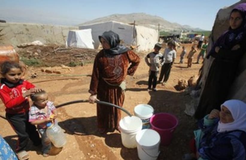 Syrian refugees fill buckets with water 370 (photo credit: REUTERS)
