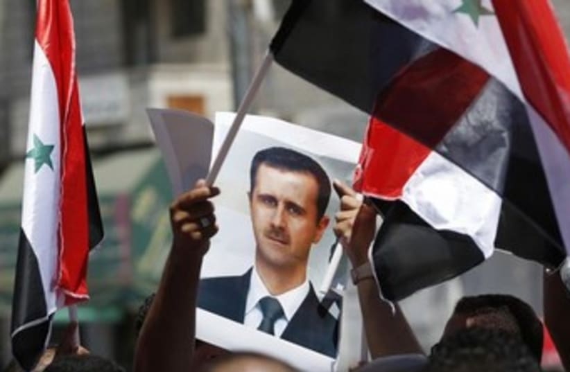 Protester holds a poster of Syria's President Bashar Assad (photo credit: Reuters)