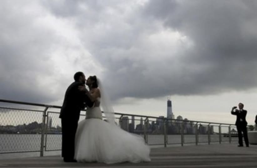 Bride and groom pose under rain clouds [illustrative] (photo credit: REUTERS/Gary Hershorn)