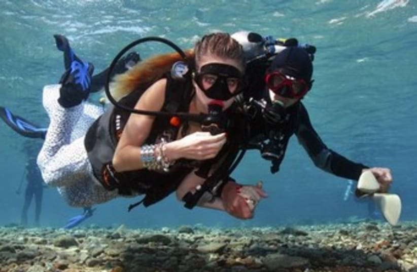 Assistant escorts a model in underwater shoot in Eilat 370 (photo credit: REUTERS)