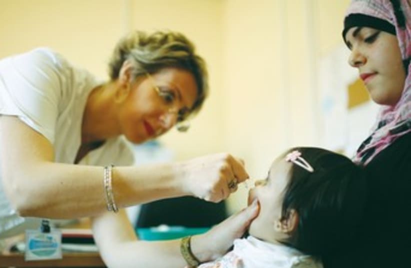 A MEDICAL staffer checks a girl  (photo credit: Marc Israel Sellem/The Jerusalem Post))