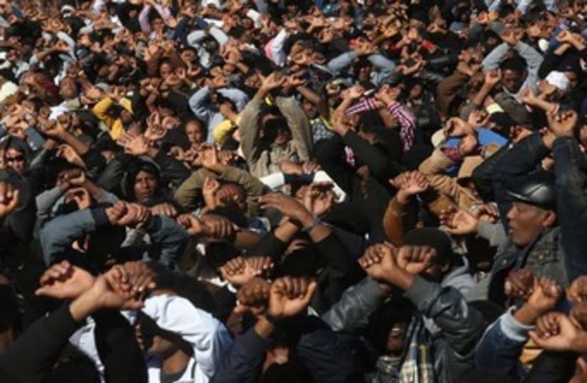 Migrants making hand gesture to signal imprisonment. (photo credit: Marc Israel Sellem/The Jerusalem Post))