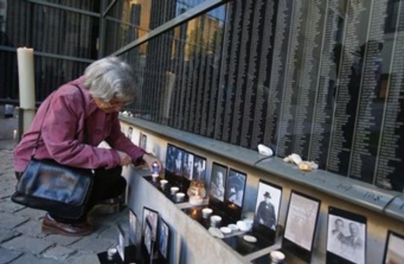 A woman lights a candle at Budapest's Holocaust Memorial Center. (photo credit: REUTERS)