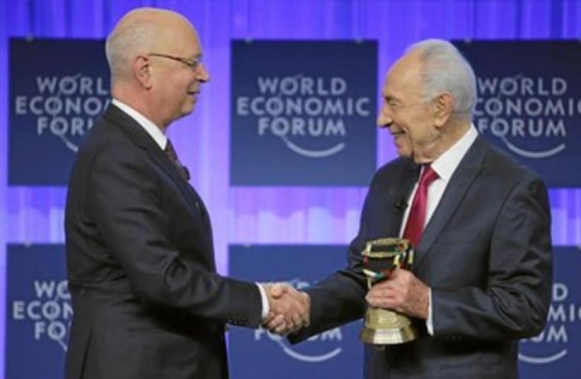 President Shimon Peres receives his award from the World Economic Forum (WEF) honoring him for his long-standing commitment to its mission and his contributions to the annual meeting program for more than two decades, during the WEF in Davos January 24, 2014.  (photo credit: COURTESY OF WORLD ECONOMIC FORUM)