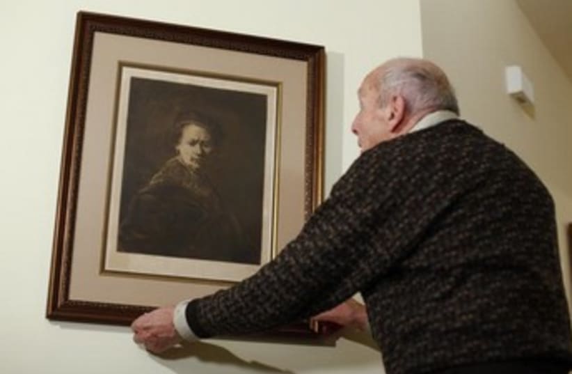 Harry Ettlinger a former member to the "Monuments Men" with a print of a Rembrandt self-portrait. (photo credit: REUTERS)