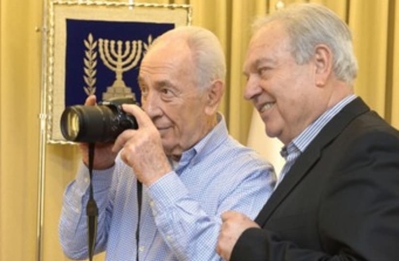 Moshe Milner shows President Shimon Peres how to use his camera. (photo credit: AMOS BEN GERSHOM, GPO)