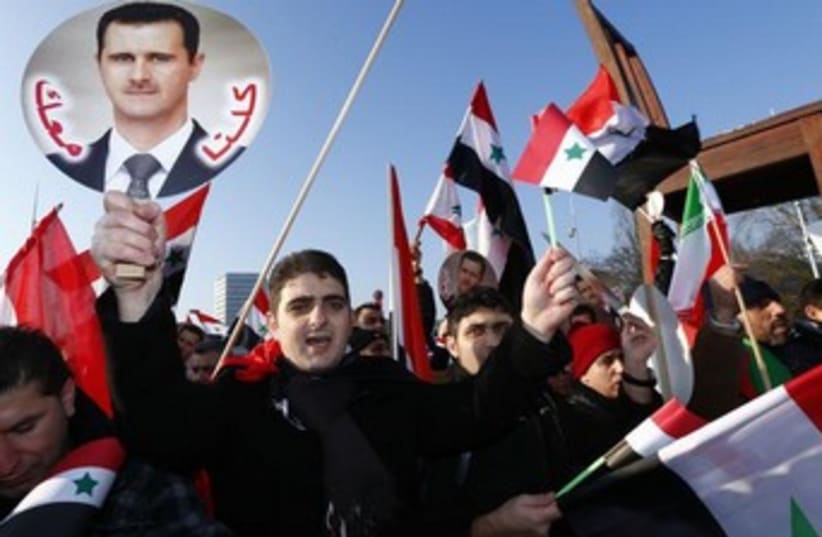 Assad supporters carry Syrian flags and portraits in front of the United Nations European headquarters in Geneva January 31, 2014. (photo credit: REUTERS)