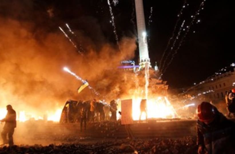 A firework explodes amid flames during clashes between anti-government protesters and riot police at Kiev's Independence Square January 18, 2014. (photo credit: REUTERS)
