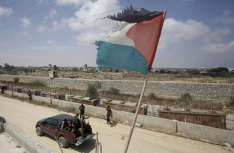  A Palestinian flag flutters above members of the Hamas security forces. (photo credit: REUTERS)
