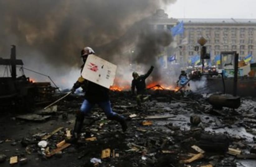 Anti-government protesters advance through burning barricades in Kiev's Independence Square February 20, 2014 (photo credit: REUTERS)