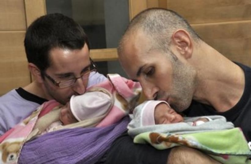 A couple with their twin babies delivered by a surrogate mother. [Illustrative] (photo credit: REUTERS)