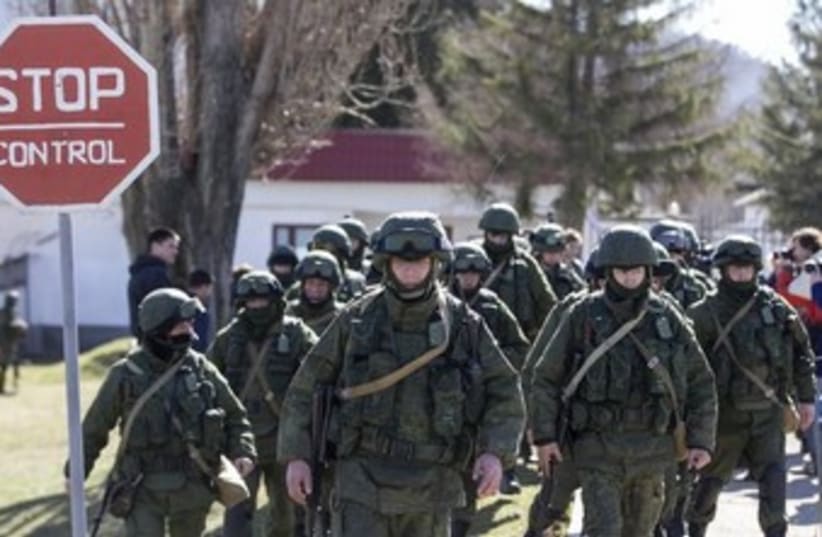 Military personnel, believed to be Russian servicemen, walk outside a Ukrainian military unit in the village of Perevalnoye (photo credit: REUTERS)