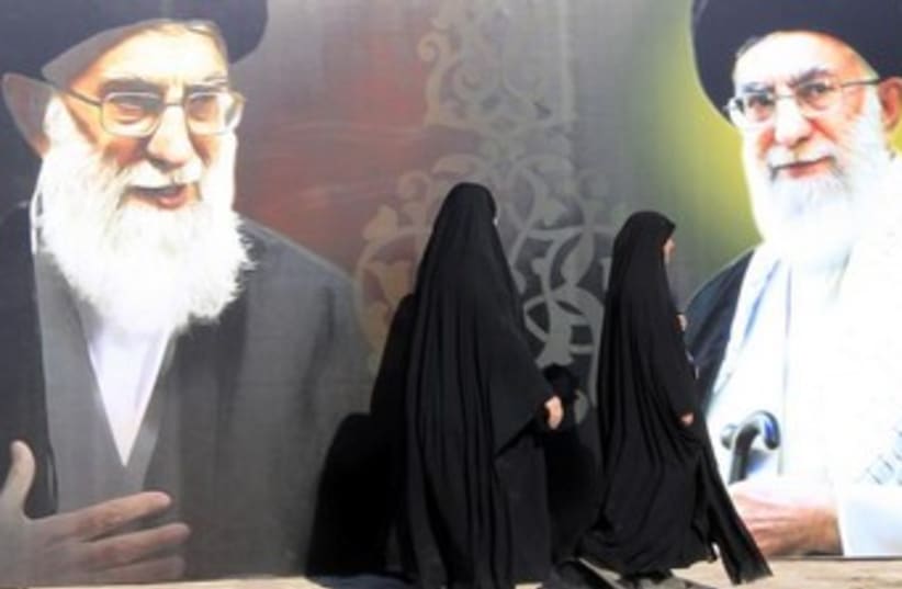 Iraqi Shi'ites walk past a mural of Iranian Supreme Leader Ayatollah Ali Khamenei. (photo credit: REUTERS)