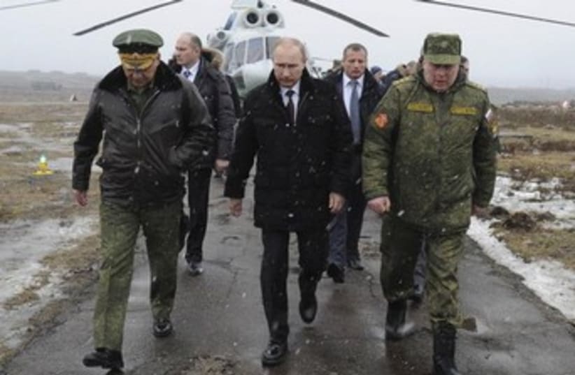 Russia's President Vladimir Putin (front C), accompanied by Russian Defence Minister Sergei Shoigu (front L), walks to watch military exercises. (photo credit: REUTERS)
