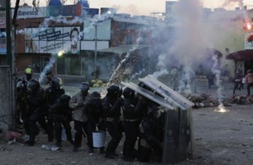 Riot police take cover from firecrackers shot by anti-government protesters during a protest against the government of Venezuela's President Nicolas Maduro at Altamira Square in Caracas March 5, 2014. (photo credit: REUTERS)