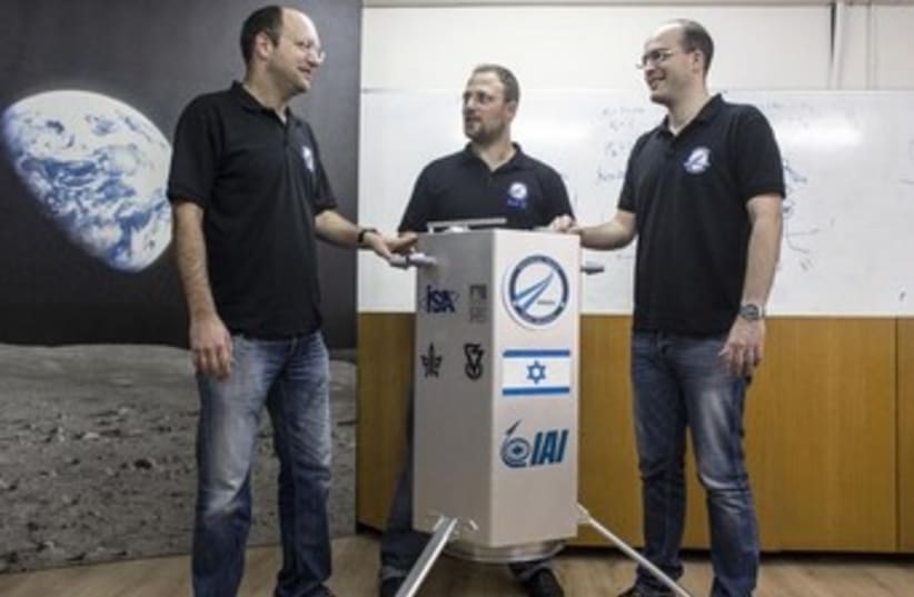 Co-founders of SpaceIL Yariv Bash (L), Kfir Damari (C) and Yonatan Winetraub stand next to their company's spacecraft process prototype, February 24, 2014. (photo credit: REUTERS)