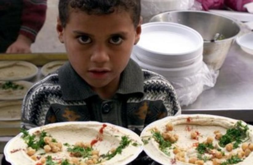 A Palestinian child in Gaza serves up dishes of hummus. (photo credit: REUTERS)