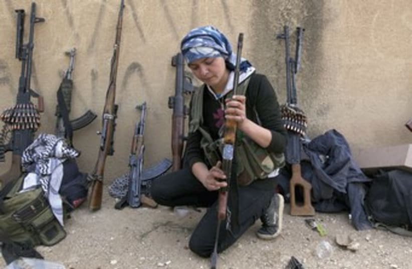 A KURDISH female fighter from Kurdish People’s Protection Units (YPG) checks her weapon near Ras al-Ain, in the province of Hasakah, after capturing it from Islamist rebels. (photo credit: REUTERS)