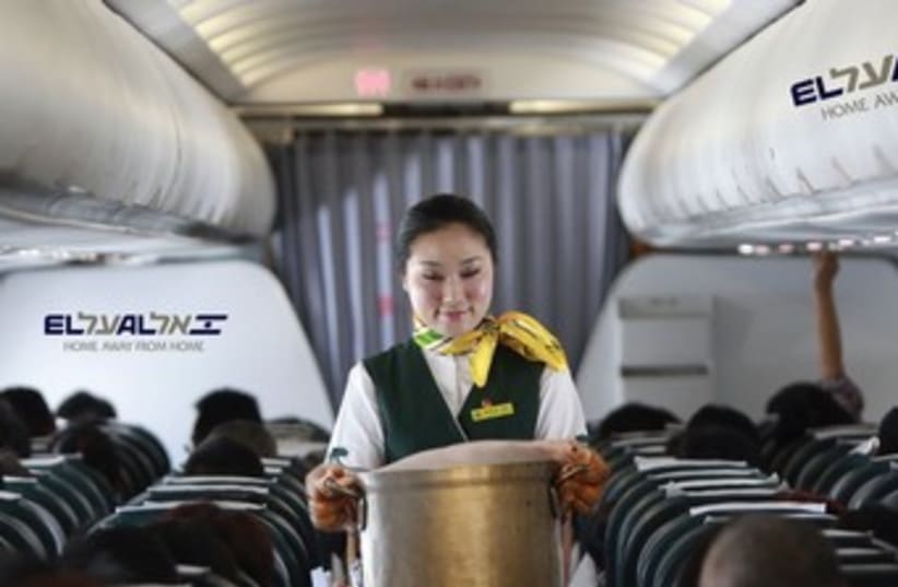 A STEWARDESS brings piping hot cholent from the galley to serve to enthusiastic passengers aboard a flight to New York. (photo credit: REUTERS)
