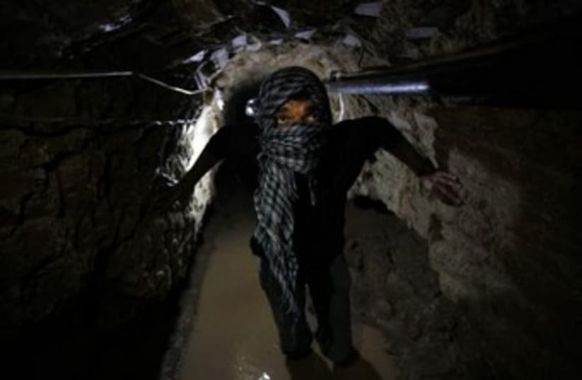 Palestinian works inside a smuggling tunnel flooded by Egyptian forces (photo credit: REUTERS)
