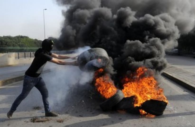 Anti-Assad protester throws tire on fire near Beirut. (photo credit: REUTERS)