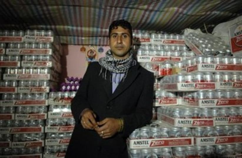 A smuggler poses with cartons of beer during an alcohol smuggling operation to Iran (photo credit: REUTERS)