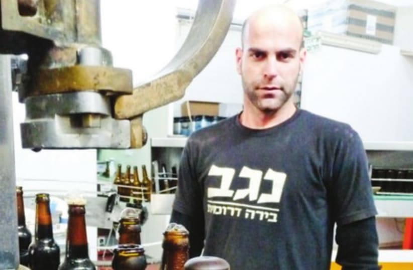 CEO SAGIV Karlboim stands near the bottle assembly line in the Kiryat Gat brewery of Negev Beer (photo credit: Courtesy)