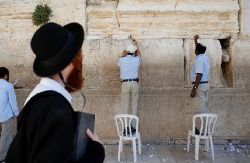Workers clean out old notes from the Western Wall ahead of the Passover holiday (photo credit: REUTERS)