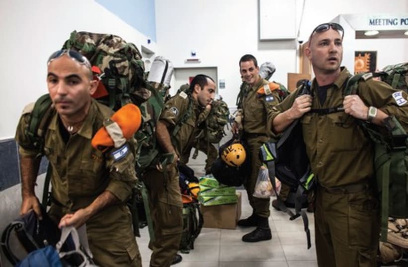 Soldiers carry their gear to a meeting point near Tel Aviv. (photo credit: REUTERS)