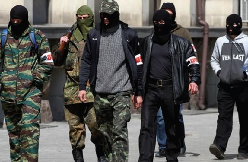 PRO-RUSSIAN GUNMEN walk past the mayor’s office in Donetsk, Ukraine, on Wednesday. (photo credit: REUTERS)