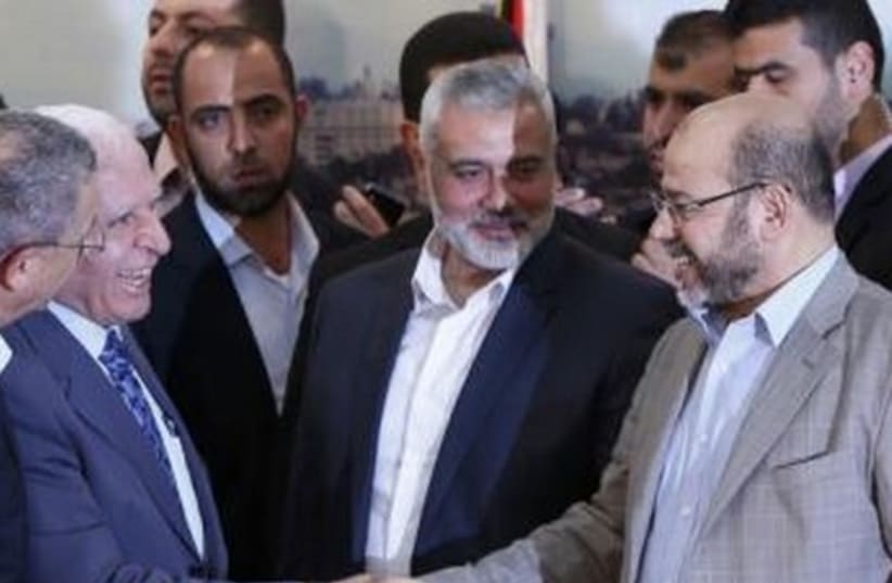 Senior Fatah official Azzam Al-Ahmed (L) shakes hands with senior Hamas leader Moussa Abu Marzouq after announcing a reconciliation agreement  (photo credit: REUTERS)