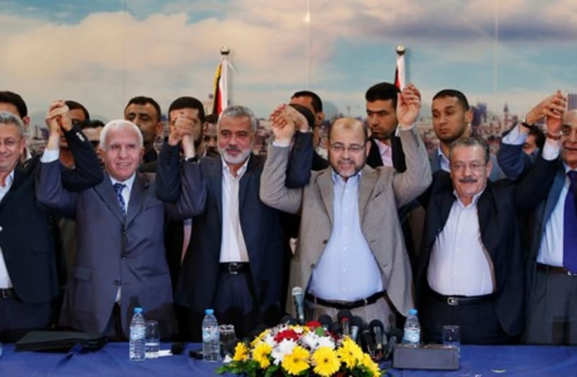 Hamas and Fatah leaders hold their hands after announcing a reconciliation agreement (photo credit: REUTERS)
