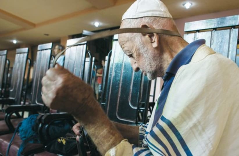A Jewish man wraps teffilin at the Central Synagogue in Havana. (photo credit: BENNY LEVIN PHOTOGRAPHY)