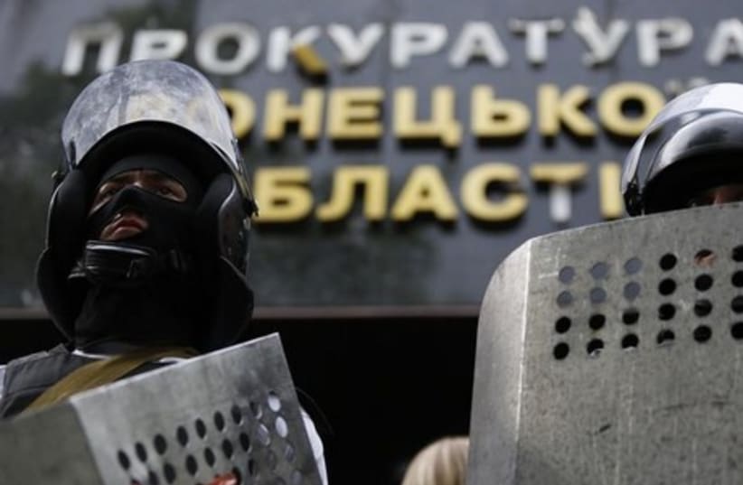 Pro-Russia activists wearing riot police helmets and shields stand guard at the entrance of the prosecutor's office in Donetsk May 1, 2014 (photo credit: REUTERS)