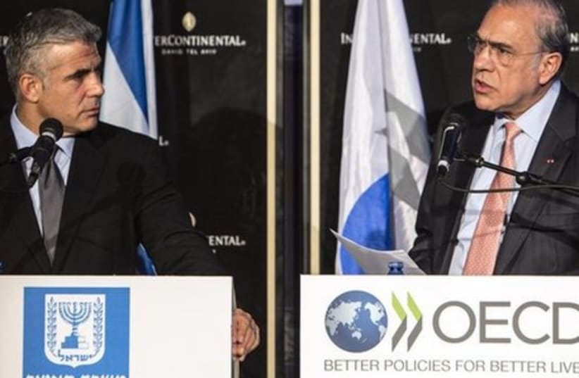 Jose Angel Gurria (R), Secretary-General of the Organization for Economic Cooperation and Development (OECD), at a news conference with Finance Minister Yair Lapid. (photo credit: REUTERS)