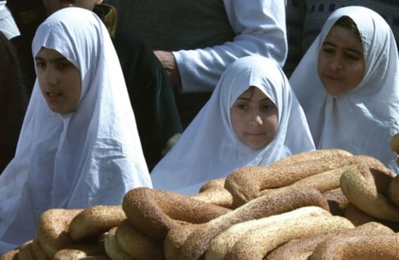 Palestinian girls pass a bread vendor in the Old City. Most Jerusalem street vendors do not have a license. (photo credit: REUTERS)