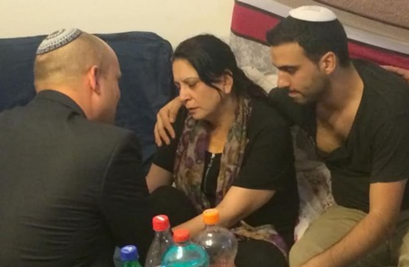 Economy Minister Naftali Bennett consoles members of the Dadon family in Afula. (photo credit: Courtesy)