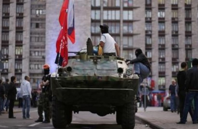 A pro-Russia rebel sits on top of an armored vehicle outside a regional government building in Donetsk, eastern Ukraine May 10, 2014. (photo credit: REUTERS)