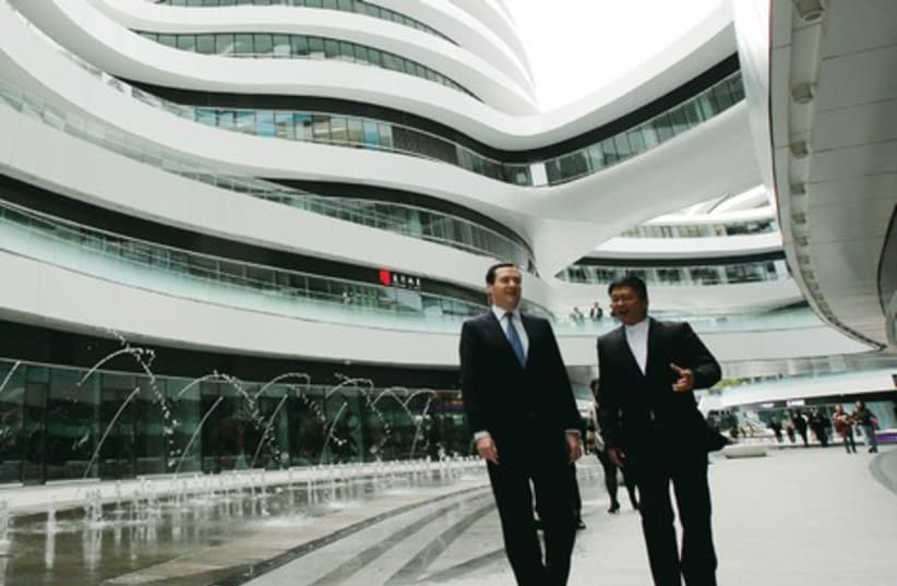 SATOSHI OHASHI (R), associate director of the Beijing Studio of Zaha Hadid Architects, accompanies Britain’s Chancellor of the Exchequer George Osborne during their tour of Galaxy SOHO, a newly-built urban complex building, in Beijing last year. (photo credit: REUTERS)