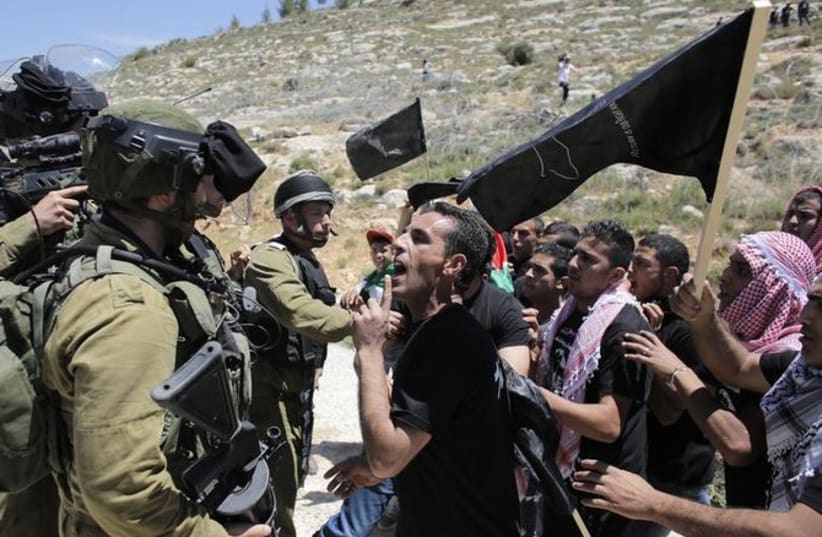 A Palestinian protester argues with IDF soldiers during a protest marking Nakba Day, May 15, 2014. (photo credit: REUTERS)