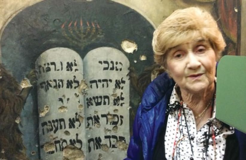 Rena Quint points out bullet holes on the wall of what once was the Piotrkow Central Synagogue and now serves as a library. ( (photo credit: Courtesy)